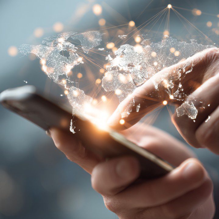 Hands using a smartphone with a glowing world map and data connections overlay, symbolizing mobile communication and digital connectivity.