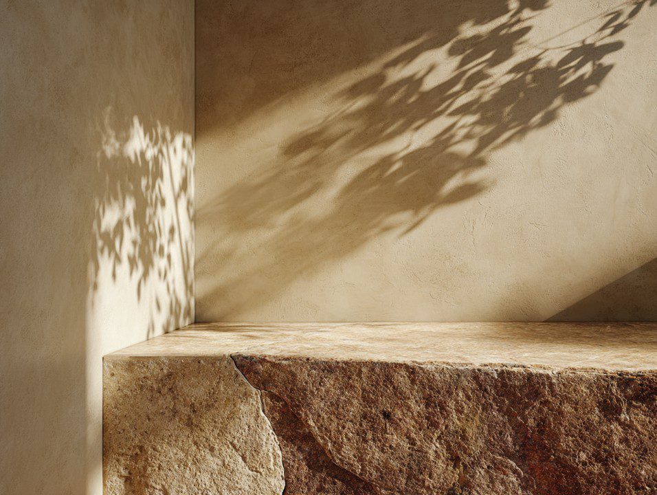 Mediterranean-style interior corner with warm stone surface and natural light casting foliage shadows on textured stucco walls.