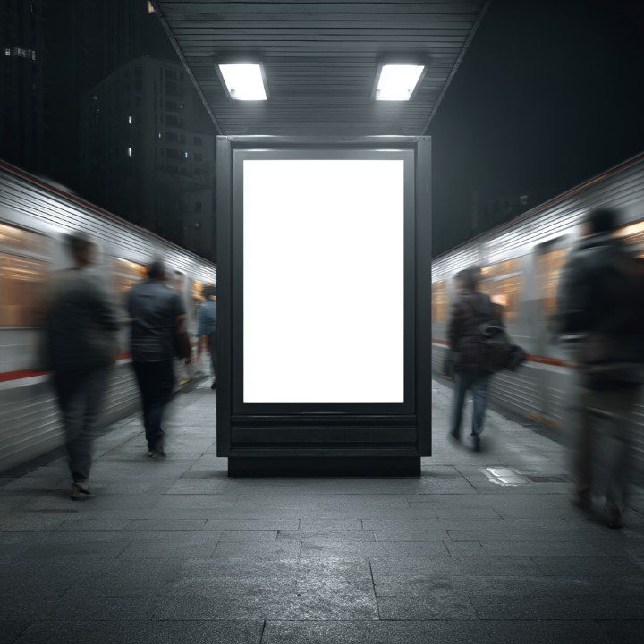 Blank vertical digital billboard mockup at a night subway station with commuters passing by—ideal for urban advertising and branding visuals.
