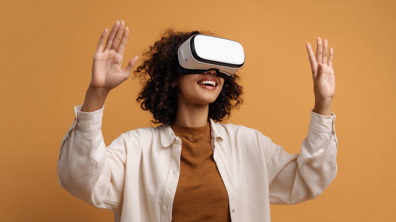 A cheerful young woman wearing a VR headset with hands raised, enjoying an immersive experience against an orange background.