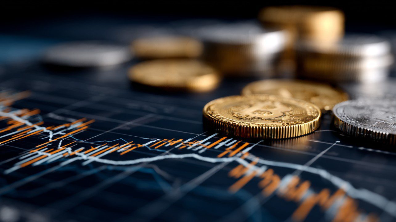 Gold and silver cryptocurrency coins, including Bitcoin, placed on a financial trading chart with price data lines.