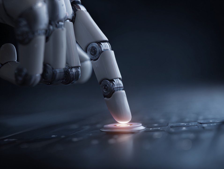 Close-up of an AI robotic hand pressing a glowing button on a computer keyboard symbolizing automation technology.