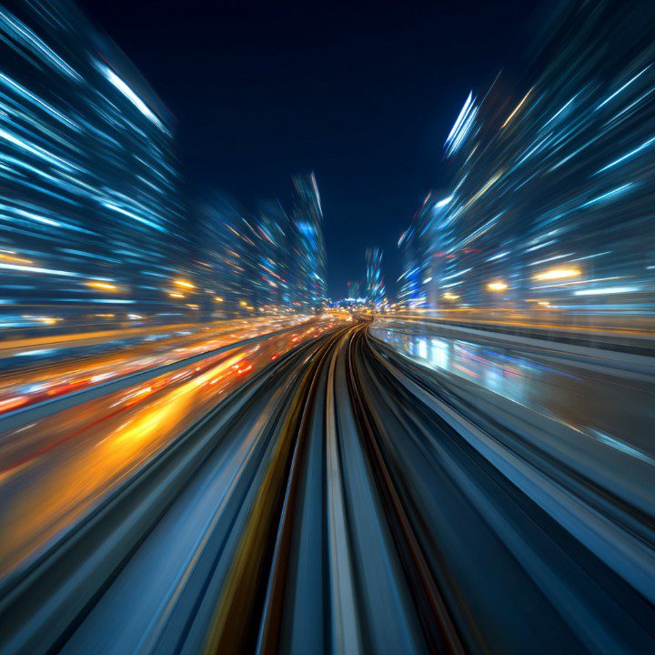 Long-exposure photograph of high-speed light trails in a futuristic night city.