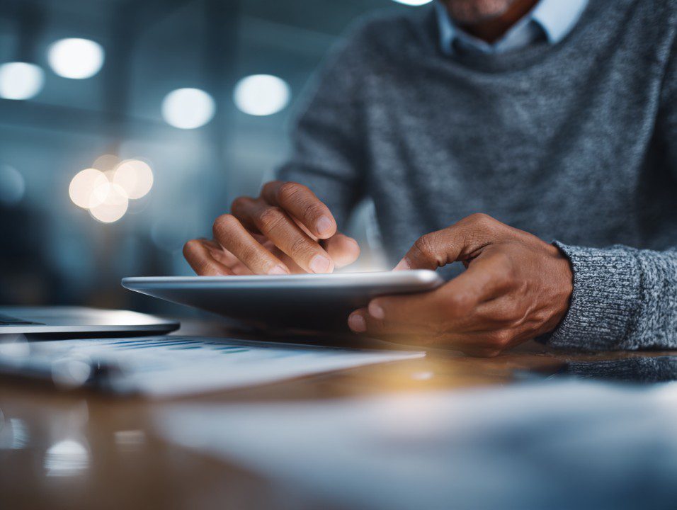 Close-up of man’s hands using a tablet in a modern office, representing productivity and digital workflow.