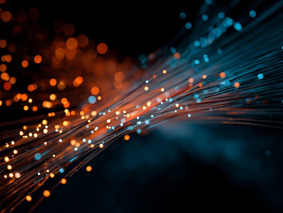 Glowing blue and orange fiber optic strands representing digital data transmission, connectivity, and modern network technology.